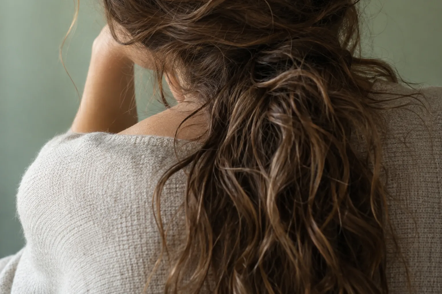 Donna vista di spalle con capelli lunghi, mossi e crespi raccolti in coda alta